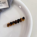 Detalle de la pinza ovalada de acetato con patrón de carey sobre plato blanco - Estampado de Leopardo Oscuro
