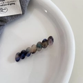 Detalle de elegantes cuentas de resina de acetato en un pasador de pelo dorado de mujer - Azul Fantasía