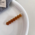 Vue détaillée d'une pince à cheveux ambrée avec cœurs sur une assiette minimaliste - Orange Caramel