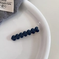 Vue détaillée d'une pince à cheveux bleue foncée en forme de cœur sur un plateau blanc - Bleu Foncé