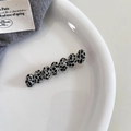 Detail view of oval acetate hair clip with black and white cow pattern on a white plate - Black White Polka Dot