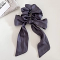Detailansicht eines tiefvioletten Satin-Haargummis mit eleganten langen Bändern auf hellem Grund - Lila