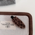 Detailed close-up of a leopard print plush hair clip on a walnut display tray - Coffee Leopard
