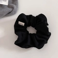 Dettaglio di elastico nero in maglia a costine con etichetta fatta a mano e texture morbida - Nero