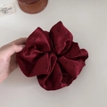 Detail eines bordeauxroten Satin-Haargummis mit schwarzen Punkten und weicher Textur - Rot