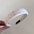Detailed shot of white velvet sponge headband with black polka dots and interior brand label - Rice White