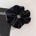 Dettaglio macro di un grande elastico scrunchie in seta nera con pieghe morbide - Grande / Nero