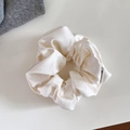 Detail of elegant ivory satin scrunchie showing glossy fabric texture and woven label - Large / Off White