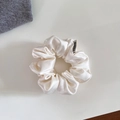 Detailed macro view of white silky satin scrunchie featuring elegant folds and black logo label - Small / Off White