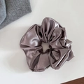 Gros plan sur un chouchou en satin soyeux gris champagne avec une texture de tissu élégante - Grand / Champagne