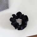 Gros plan d'un chouchou élégant en satin noir avec texture en soie et détails plissés - Petit / Noir