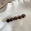 Dettaglio macro di perle in acetato tartarugato su una clip per capelli dorata - Tartarugato Chiaro
