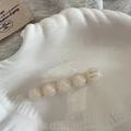 Détail macro d'une barrette fait main en perles marbrées dans un plateau coquillage - Blanc Irisé