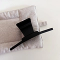Detail of a large matte black shark clip on a textured fabric background for hair styling - Matte Black
