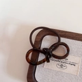 Dettaglio dell'elastico per capelli in resina tartarugata su un vassoio portagioie elegante - Marmo Blu Caffè