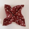 Gros plan d'une pochette de costume rouille à fleurs montrant la texture et les bords - Rouge Floral (Style Foulard Carré)