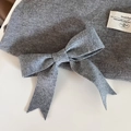 Detail einer grauen gestrickten Haarklammer mit Schleife und Stoffetikett im French-Stil - Hellgrau