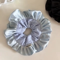 Detail of light blue satin oversized scrunchie with layered ruffles and brand label - Light Blue
