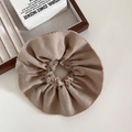 Detail of a beige textured fabric scrunchie with scalloped edges on a wooden stand - Khaki