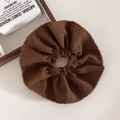 Close-up of dark brown knitted hair scrunchie with soft texture and wavy edges - Brown