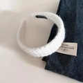 Detailed close-up of a white knitted headband with a black Hand Made fabric label - White