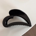 Macro shot of glossy black hollow heart-shaped hair claw clip with a polished finish - Black