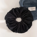 Detailed view of large black pleated scrunchie with shimmering texture and refined folds - Black