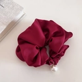 Dettaglio di uno scrunchie in raso bordeaux con grande perla bianca e anello d'oro - Rosso