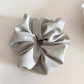 Close-up of light gray fabric scrunchie with rich folds and soft textile texture - Green