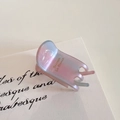 Close-up of a gradient acetate hair claw clip with pearlescent finish and gold lettering - Aurora Pink