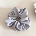 Detailed macro view of light purple scrunchie fabric with a branded bow label tag - Blue