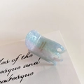 Detail of blue acetate hair claw clip showing marble texture and golden logo print - Pastel Blue