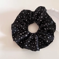 Grande elastico scrunchie in raso nero a pois bianchi su uno sfondo bianco minimalista - Nero