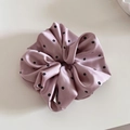 Detail eines Satin-Haargummis mit Blumendruck und seidiger Textur für Zopffrisuren - Rosa