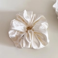 Detail of elegant pearl white satin scrunchie showing glossy fabric texture and soft folds - Off-white