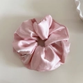 Macro detail of glossy pink satin scrunchie showing fabric texture and pleated folds - Pink