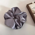 Detailed shot of grey satin scrunchie with a white pearl on a wooden jewelry display - Purple