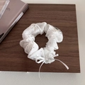 Scrunchie a righe bianche con fiocco e glitter argentati su sfondo legno scuro - Fiocco Bianco