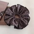 Detail eines übergroßen floralen Haargummis in Braun mit weißem Muster auf Holz - Groß / Kaffee Blumig