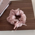 Dettaglio di elastico a righe rosa con strass e un dolce fiocco su fondo in legno - Fiocco Rosa