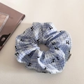 Chouchou à carreaux bleu et blanc avec motifs de nœuds et étiquette de marque sur surface - Bleu