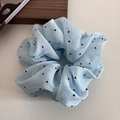 Gros plan détaillé d'un chouchou en organza bleu clair avec élégant imprimé à pois noirs - Bleu