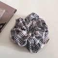 Détail d'un chouchou à carreaux avec motifs de nœuds et étiquette de marque tissée - Noir