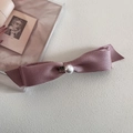 Détail du nœud en satin avec perle et pendentif cœur doré sur un fond crème élégant - Rose