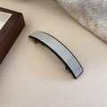Detailed view of grey acetate hair clip with black border on a warm beige background - Gray Blue