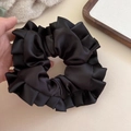 Detailed view of large black satin scrunchie featuring elegant ruffled edges and smooth texture - Black