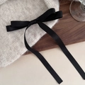 Oatmeal knitted hair clip with a long black satin ribbon bow on a wooden surface - Black