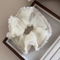 Chouchou élégant en organza crème avec bords effilochés sur un plateau en bois - Beige