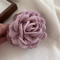 Détail d'une pince à cheveux rose 3D en tissu vieux rose avec des pétales superposés - Rose