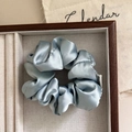 Light blue satin scrunchie with silky texture placed in a wooden jewelry box - Blue